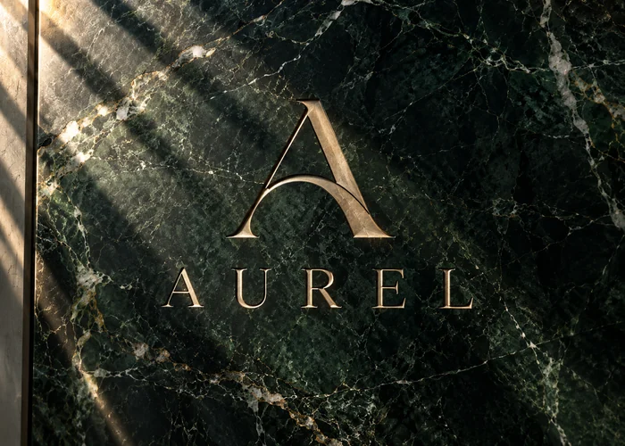 Aurel: Identidad minimalista en latón sobre mármol oscuro. Concepto original de muestra.